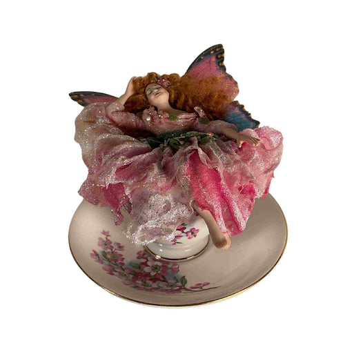 Handmade porcelain fairy sleeping in a tea cup.